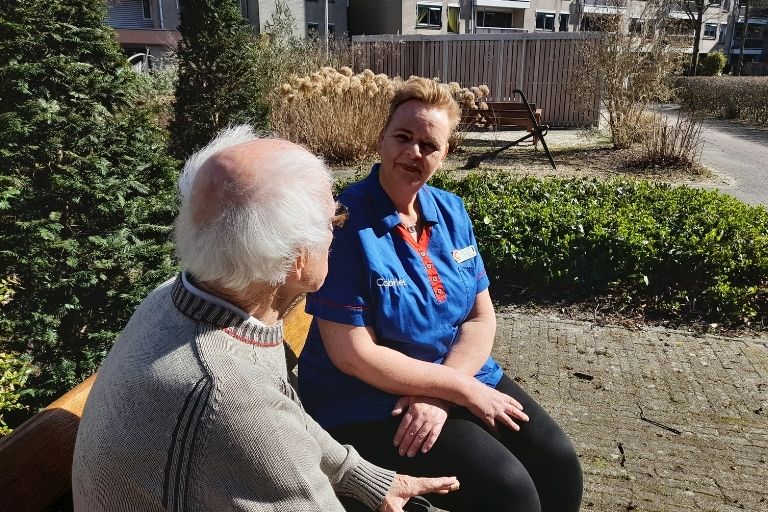 Verzorgende met bewoner de hoven